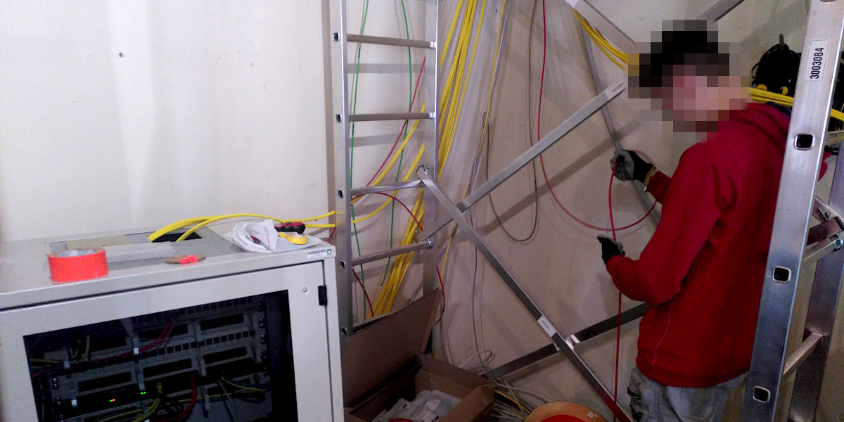 Person mit Kabel in der Hand, viele Kabel im Hintergrund