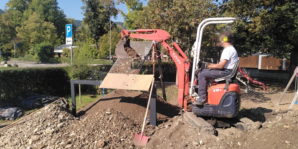 Kleinbaggger wirft Erde auf ein Sieb